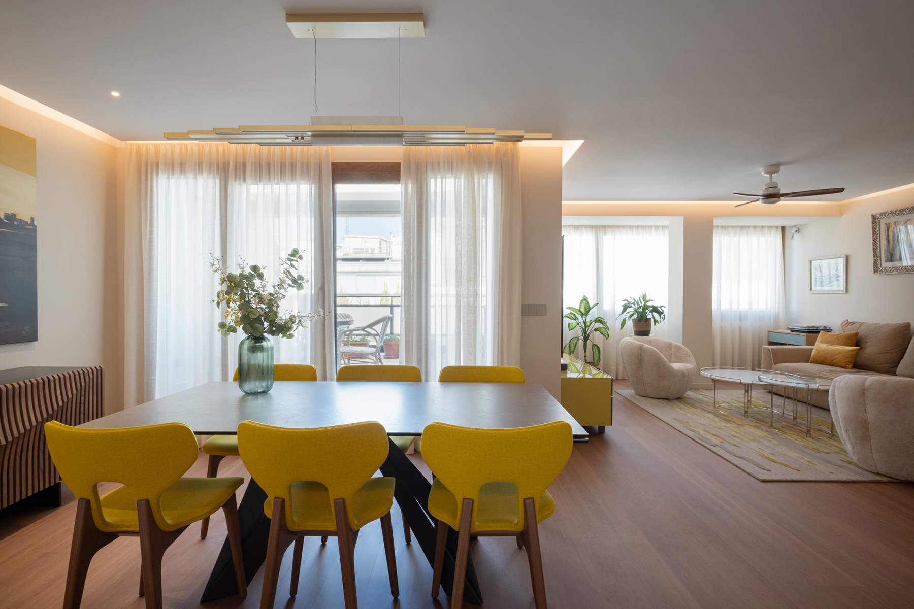 Salón-comedor de un ático reformado en Zaragoza con espacio abierto, pavimento continuo de madera, iluminación indirecta y acceso a terraza